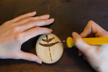 Close-up of female hands making a tree twig sign on wooden disc. - 420219852
