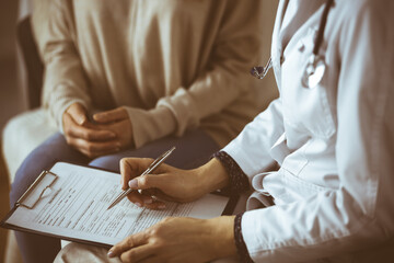 Obraz premium Unknown woman-doctor and patient discussing current health examination while sitting indoors. Stay at home concept during Coronavirus pandemic and self isolation quarantine