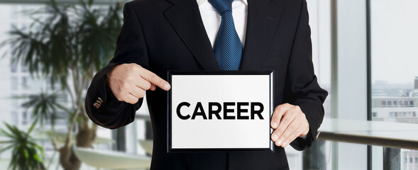 Businessman holds a signboard and points his finger to the word career. Business career