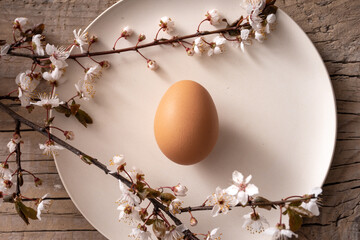 Easter table with egg plate and cherry blossom branches on rough wooden boards
