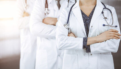 Doctors standing as a team with arms crossed in sunny clinic. Medical help, insurance and medicine concept