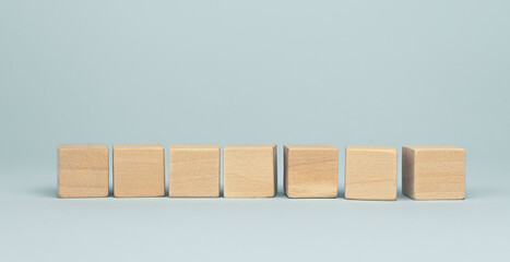 Seven blank wooden cube blocks on blue background