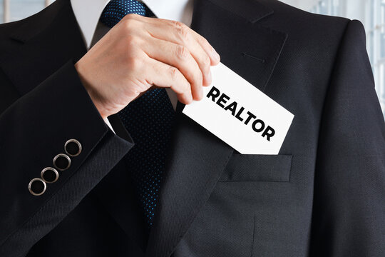 Businessman takes out a business card with the word realtor. Real estate expert concept.