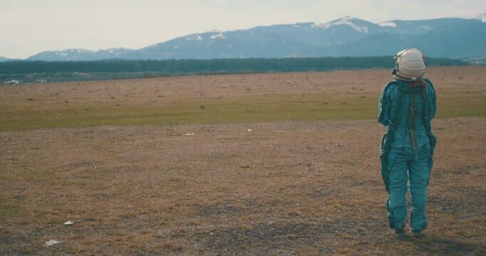 Full suit female spaceman on gorund looking to the terrain.