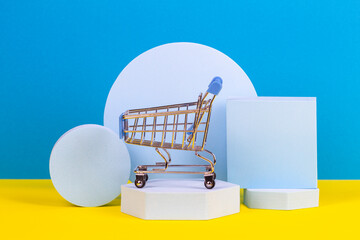 Mini shopping trolley cart with geometric podium platforms on yellow and light blue background....