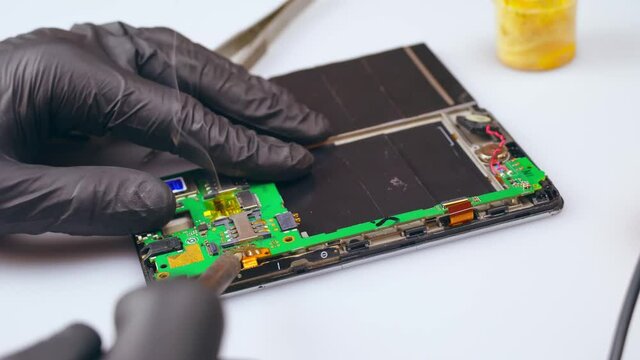 Repair of electronics with the help of a tester.The repair technician tests the electronic board by moving the test leads from one contact on the board to the other. in the frame, only the gloved hand