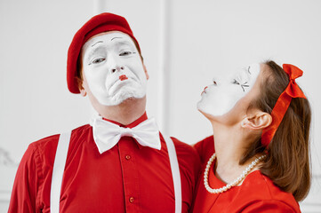 Two mime artists in red costumes, kissing scene