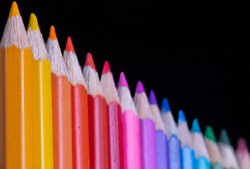a row of colored pencils on a black background