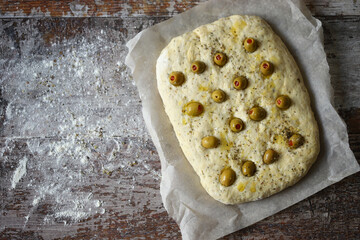 Italian focaccia with olives before baking. Raw ciabatta. Cooking focaccia with olives.