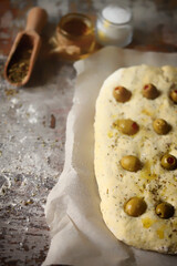 Italian focaccia with olives before baking. Raw ciabatta. Cooking focaccia with olives.