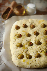 Italian focaccia with olives before baking. Raw ciabatta. Cooking focaccia with olives.