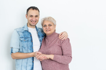 family, generation and people concept - happy smiling senior mother with adult son hugging at home