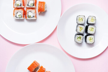 sushi and rolls on white plates on a pink background. Japanese kitchen. Sushi menu. Assorted sushi. cope spyce. flat lay