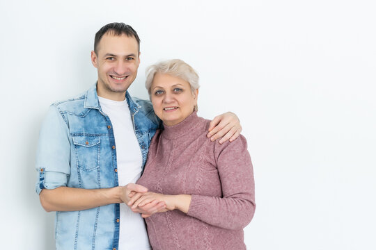 Family, Generation And People Concept - Happy Smiling Senior Mother With Adult Son Hugging At Home