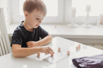 5 year old boy playing loto at the white table