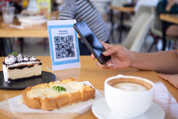 Women's hands are using  the phone to scan the qr code to select food menu. Scan to get discounts or pay for food. The concept of using a phone to transfer money or paying money online without cash.