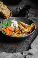 Thin pancakes with herbs, salmon and cream cheese on a plate. crepes