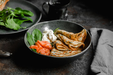 Thin pancakes with herbs, salmon and cream cheese on a plate. crepes