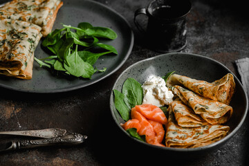 Thin pancakes with herbs, salmon and cream cheese on a plate. crepes