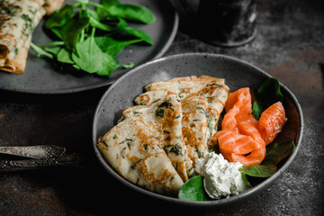 Thin pancakes with herbs, salmon and cream cheese on a plate. crepes