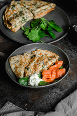 Thin pancakes with herbs, salmon and cream cheese on a plate. crepes
