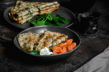 Thin pancakes with herbs, salmon and cream cheese on a plate. crepes