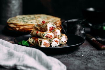 Thin pancakes with herbs, salmon and cream cheese on a plate. crepes