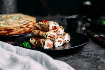 Thin pancakes with herbs, salmon and cream cheese on a plate. crepes