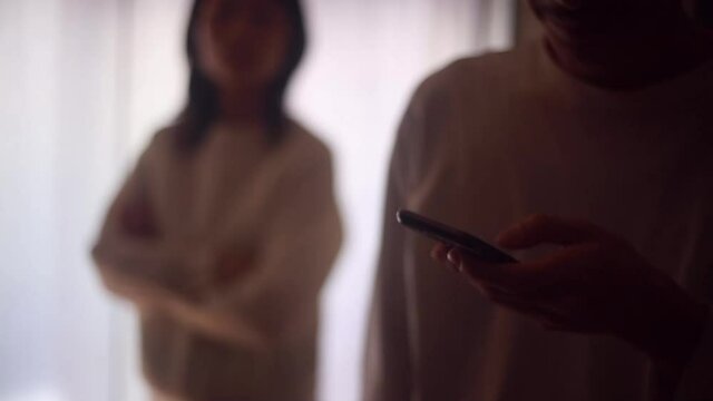 スマートフォンを操作する男性と不審に思う女性
