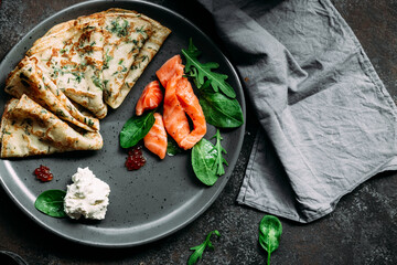 Thin pancakes with herbs, salmon and cream cheese on a plate. crepes