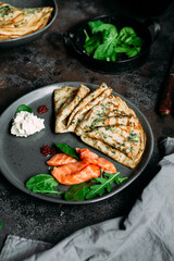 Thin pancakes with herbs, salmon and cream cheese on a plate. crepes