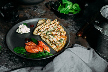 Thin pancakes with herbs, salmon and cream cheese on a plate. crepes