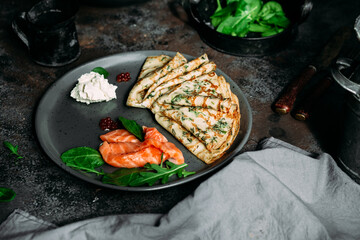 Thin pancakes with herbs, salmon and cream cheese on a plate. crepes