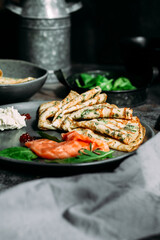 Thin pancakes with herbs, salmon and cream cheese on a plate. crepes