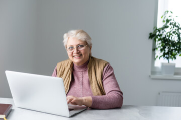 Elderly woman having a video call with her family, smiling and waving. Quarantine time