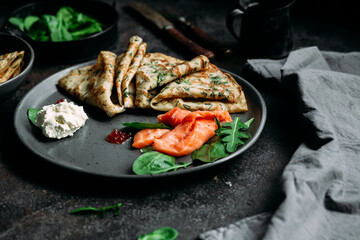 Thin pancakes with herbs, salmon and cream cheese on a plate. crepes