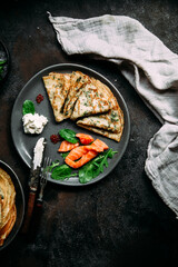 Thin pancakes with herbs, salmon and cream cheese on a plate
