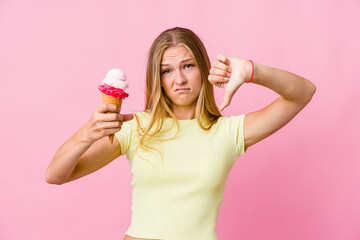 Young russian woman eating an ice cream isolated showing thumb down and expressing dislike.