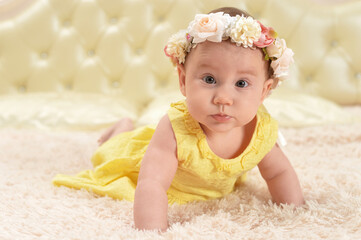 cute little baby girl in wreath   on bed