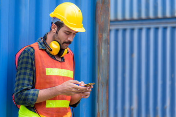 Young confident man engineer using digital tablet and wearing yellow safety helmet and check for control loading containers box from Cargo freight ship for import and export, transport.