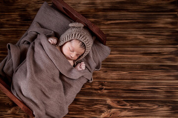 Newborn baby, beautiful infant lies in brown fur blanket on wood background, 10 days old girl sleeping in the bed. Copy space © volody10