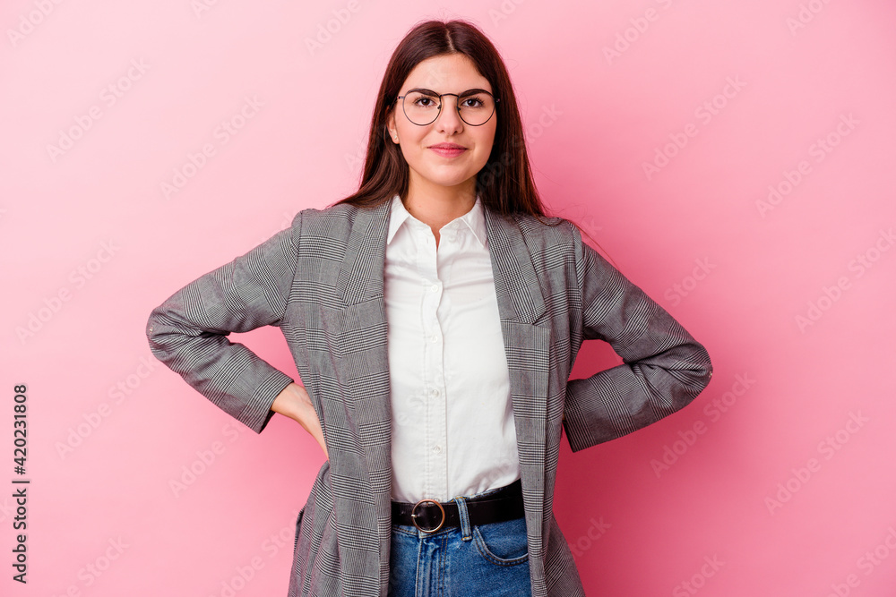 Wall mural Young caucasian business woman isolated on pink background confident keeping hands on hips.