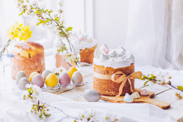 Traditional ukrainian easter cake with white swiss meringue. New cruffin cake trend 2024. Spring cherry blossom and colorful painted eggs. Person decorates cake with hand. Free copy space