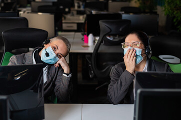 Two women in protective masks are bored at work. Call center operators at the desk