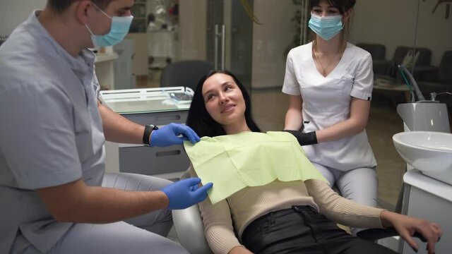 Young Caucasian woman sits in a chair at the dental clinic. Preparing for the examination of a patient in the hospital. The dentist prepares to examine the patient.