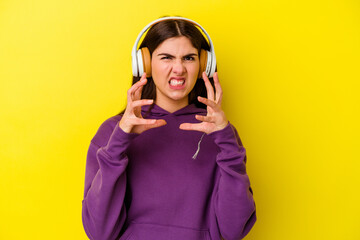 Young caucasian woman listening to music with headphones isolated on pink background upset...