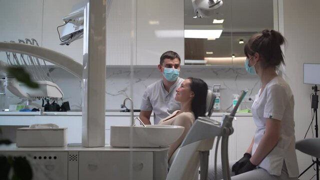 An orthodontist discusses with a patient a facial recovery and rehabilitation plan after an accident, looking at an x-ray image on a monitor screen.