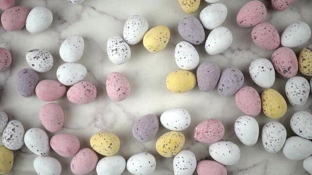 Easter chocolate mini eggs in pretty pastel colours. Top down slow motion pan across the candy.