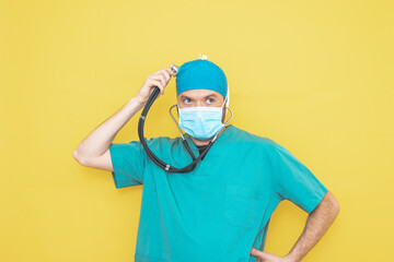 Surgeon dressed in operating theatre uniform and stethoscope, on yellow background.