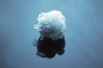 Crumpled plastic wrap on a blue surface with reflection.